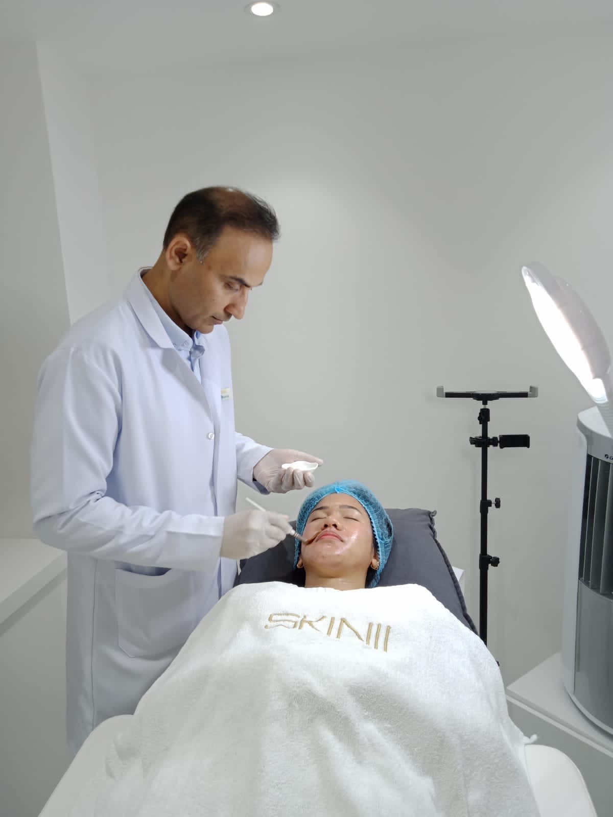 Dr. Zaheer Abbas beside a patient at SKIN111
